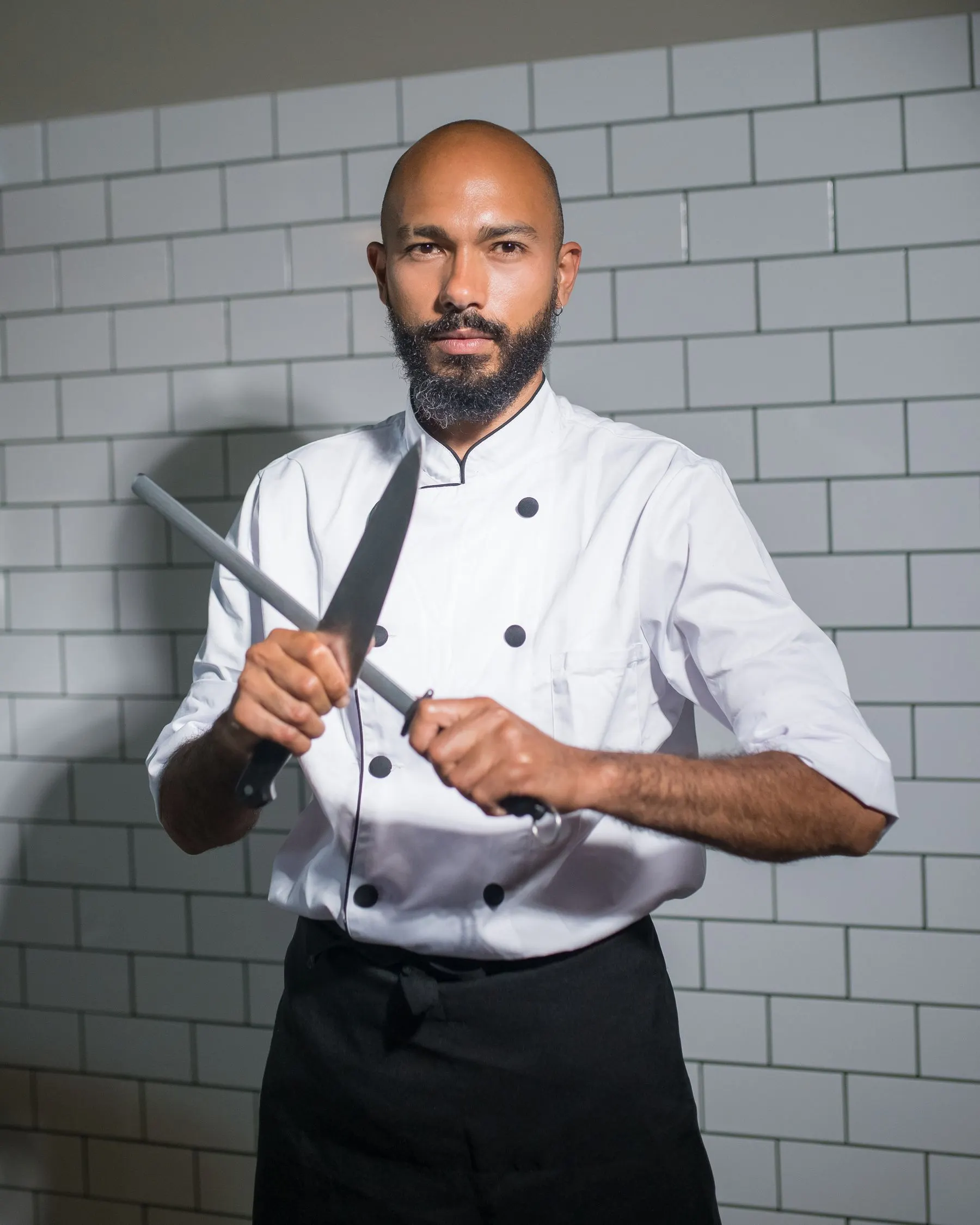 Chef Julien Moreau holding a knife in a tiled professional kitchen